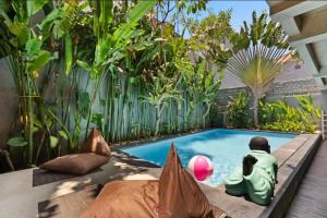 a swimming pool in the middle of a garden at Modern Apartment with Shared Pool - By the Beach in Seminyak