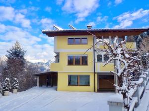 a yellow building with snow on the ground at Alps Living Söll in Söll