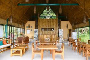 a restaurant with wooden tables and chairs and windows at Mbeliling Mountain Ecolodge in Noca