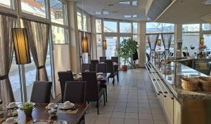 a dining room with tables and chairs and windows at Hotel Prignitz in Wittenberge