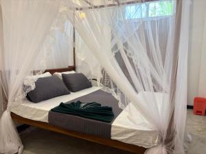 a bed with white drapes in a room at Minuda Villa in Kamburugamuwa