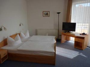 a bedroom with a bed and a desk with a television at Hotel Prignitz in Wittenberge