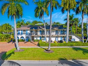 a large white house with palm trees in front of it at Le Monaco - 1 BR Romantic Condo! Getaway Steps from 5th Ave S Stylish Coastal Retreat with King Bed Beach Access and Prime Location, Near Dining Shopping and Sunset Views! in Naples