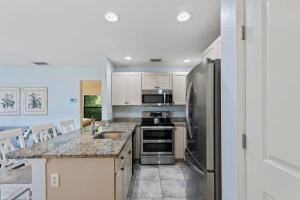 a kitchen with a stainless steel refrigerator and appliances at Le Monaco - 1 BR Romantic Condo! Getaway Steps from 5th Ave S Stylish Coastal Retreat with King Bed Beach Access and Prime Location, Near Dining Shopping and Sunset Views! in Naples