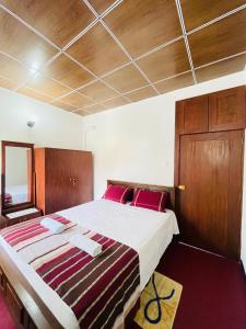 a bedroom with a large bed with red pillows at Anu Home Stay in Ahangama