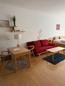 a living room with a red couch and tables at Lindenhof Deutsch in Bad Tatzmannsdorf