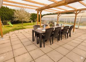 a patio with a table and chairs under a pergola at Villa au calme, piscine couverte chauffée 365j in Thiberville