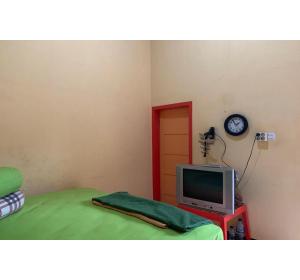 a room with a television and a clock on the wall at Hotel O Wisma Rima Melati in Tolo +16 photos