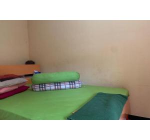a room with a green bed with two pillows on it at Hotel O Wisma Rima Melati in Tolo