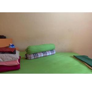 a room with a bed with green sheets and blankets at Hotel O Wisma Rima Melati in Tolo