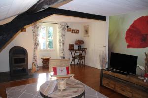 a living room with a tv and a table at Moulin des Faurilloux in La Chapelle-Faucher
