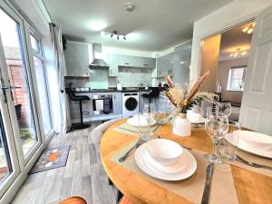 a dining room with a table with plates and wine glasses at The Charm Luxury House - 8mins to NEC, Birmingham Airport in Marston Green