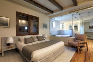 ein Schlafzimmer mit einem Bett und einem Stuhl und einer Badewanne in der Unterkunft El Boutique Hotel in Tyros + 78 Fotos