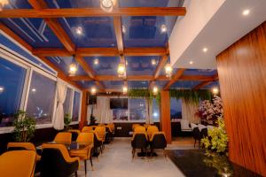 a room with yellow chairs and tables and windows at Hotel Orchid Imphal in Imphal