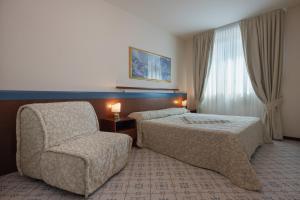 a bedroom with a bed and a chair and a window at Aparthotel Holiday in Bibione