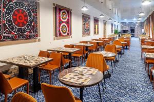 a row of tables and chairs in a restaurant at Zarafshon Garden Hotel in Bukhara