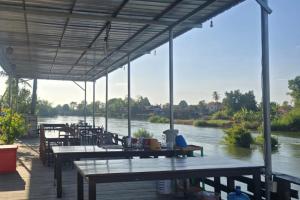 a covered deck with tables and chairs next to a river at Nongsak Riverside Guesthouse & Nongsak Guesthouse in Ban Khon