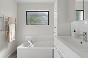 a white bathroom with a sink and a window at Welcome Bay Stay in Tauranga +21 photos