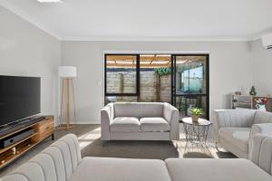 a living room with white furniture and a tv at Welcome Bay Stay in Tauranga