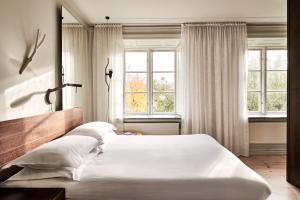 a bedroom with a large white bed with windows at Hotel Skeppsholmen, Stockholm, a Member of Design Hotels in Stockholm