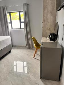 a room with a kitchen with a table and a yellow chair at Marble Crest Guest House in Maun +4 photos