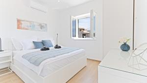 a white bedroom with a bed and a window at Luxury Apartment Nala with shared pool in Sevid