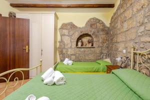 a bedroom with two green beds and a stone wall at The Stone House Historic Center in Grotte di Castro