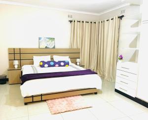 a bedroom with a large bed and a dresser at Asamez Apartments in Lilongwe