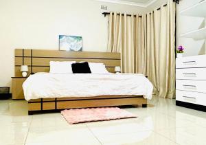 a bedroom with a large bed and a pink rug at Asamez Apartments in Lilongwe