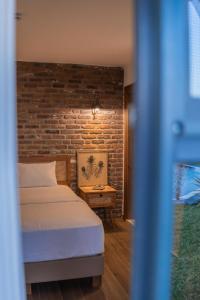 a bedroom with a bed and a brick wall at Kaira Kazdaglari in Edremit