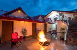 a patio with chairs and a fire in front of a house at Hotel Kullu Valley in Kulu