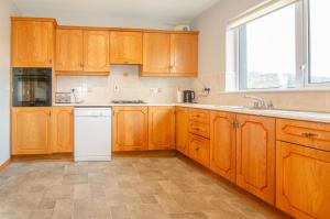 a kitchen with wooden cabinets and a white dishwasher at Sea View Heights in Rathmullan