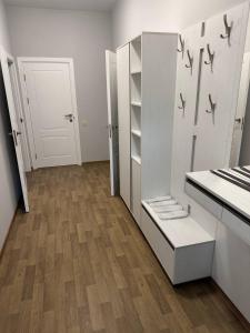 a kitchen with white cabinets and a wooden floor at Надія in Khlibodarske