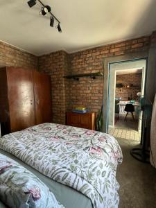 a bedroom with a bed and a brick wall at Your home in the Cape in Cape Town