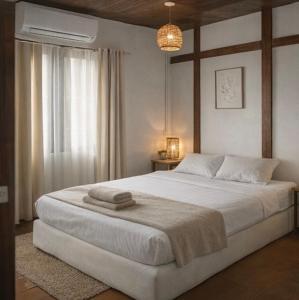 a bedroom with a large white bed with a window at Bird Nest in Ko Tao