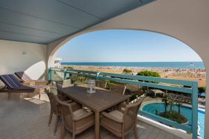 a balcony with a table and chairs and a pool at Aparthotel Imperial in Bibione