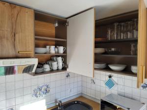 a kitchen with white tile and cabinets with dishes at Ferienwohnung Renate in Siegsdorf +18 photos