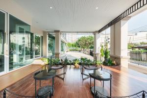an empty lobby with tables and chairs and windows at ZAYN Bangna Hotel in Bangna
