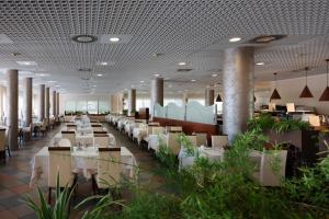 a restaurant with white tables and chairs and plants at Aparthotel Imperial in Bibione