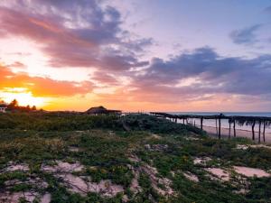 a sunset over a beach with a pier and the ocean at Container House in Sisal +13 photos
