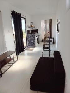 a living room with a black couch and a kitchen at Container House in Sisal