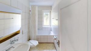 a white bathroom with a tub and a sink at Functional Stay with Balcony in Zurich