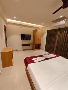 a bedroom with a bed and a tv in a room at Neelram Hospitality in Mangalore