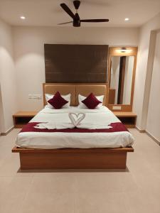 a bedroom with a large bed with red pillows at Neelram Hospitality in Mangalore +3 photos