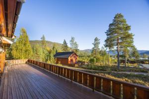 a wooden deck with a cabin in the woods at Marits Hytte 6p in Vradal