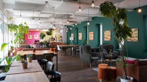 a restaurant with green walls and tables and chairs at Hostel by Hyve Basel in Basel +103 photos
