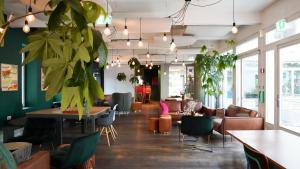 a room with plants and tables and chairs at Hostel by Hyve Basel in Basel