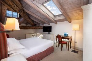 a bedroom with a bed and a desk with a laptop at Grand Hotel della Posta, WorldHotels Distinctive in Sondrio