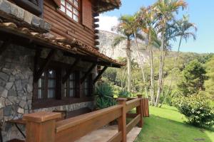 a porch of a house with a bench and palm trees at Pousada Peterle in Domingos Martins