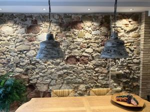 a stone wall with two lights hanging over a table at L' Alzina in Falset